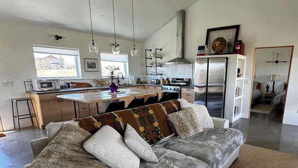 A modern living room with a grey sofa, a coffee table, and a kitchen in the background. - Casa de Los sueños del mañana (El Prado)