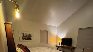 A bedroom with a bed, a desk, a chair, a television, and a ceiling light fixture. - Casa de Los sueños del mañana (El Prado)