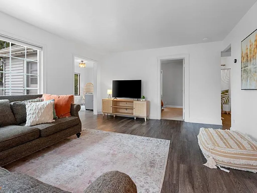 A modern living room with a sofa, a TV, and a wooden cabinet.