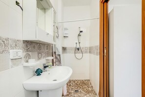 A bathroom with a sink, mirror, shower, and patterned tiles. - Stella Marina Apartment 8, Vieste, Italy (Vieste)