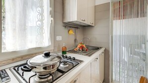 Een keuken met een fornuis, gootsteen en raam met gordijnen.