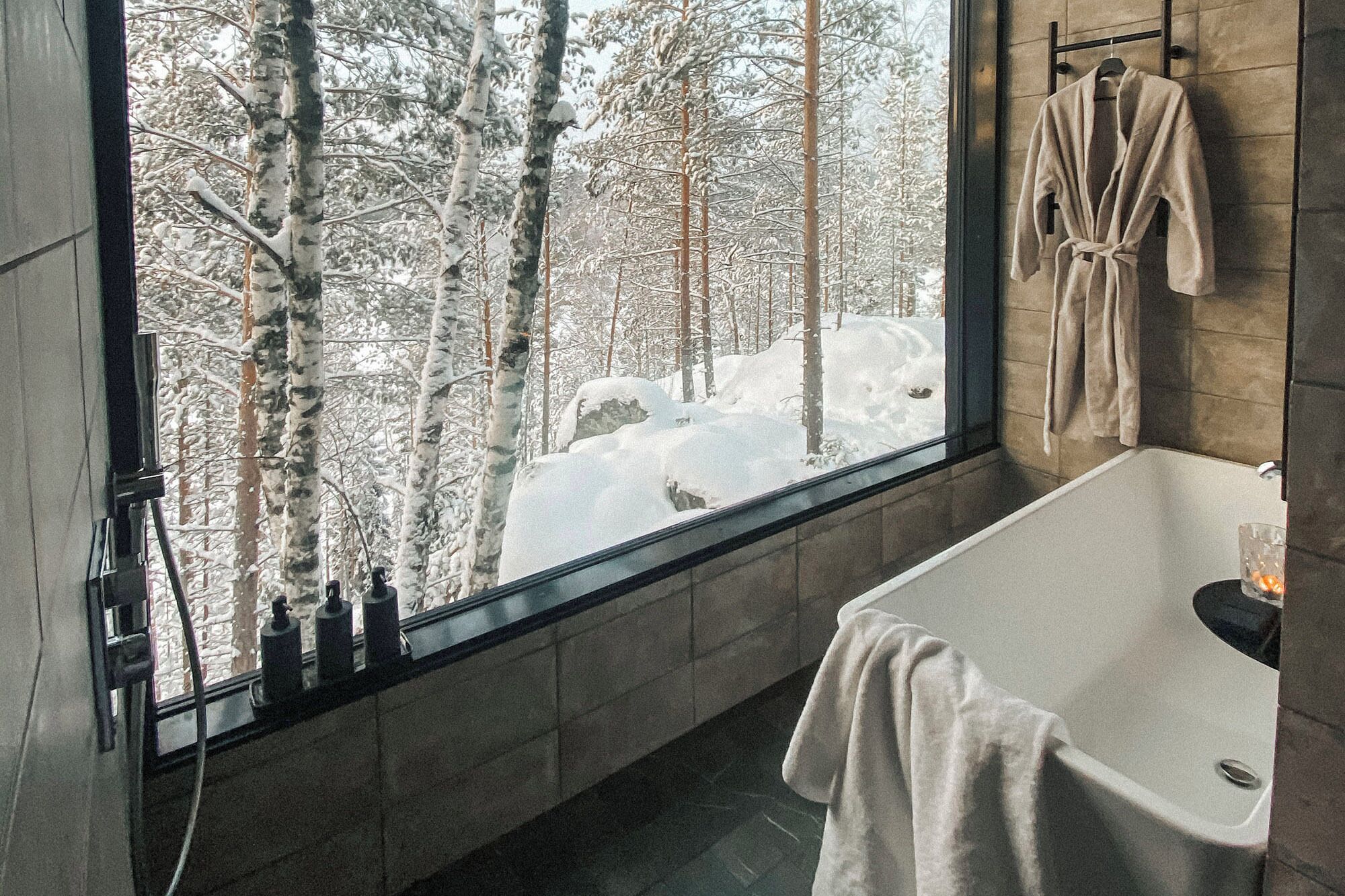Un baño moderno con un ventanal grande, una bañera y un perchero para toallas.