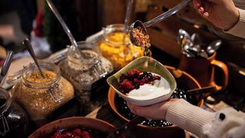 A person holding a bowl of yogurt with berries and granola.