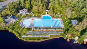 An aerial view of a resort with a large swimming pool, a tennis court, and a boat dock. - Peaceful Two-Story Lake Naomi Home, Modern Design in Timber Trails + Lake Access (Pocono Pines)