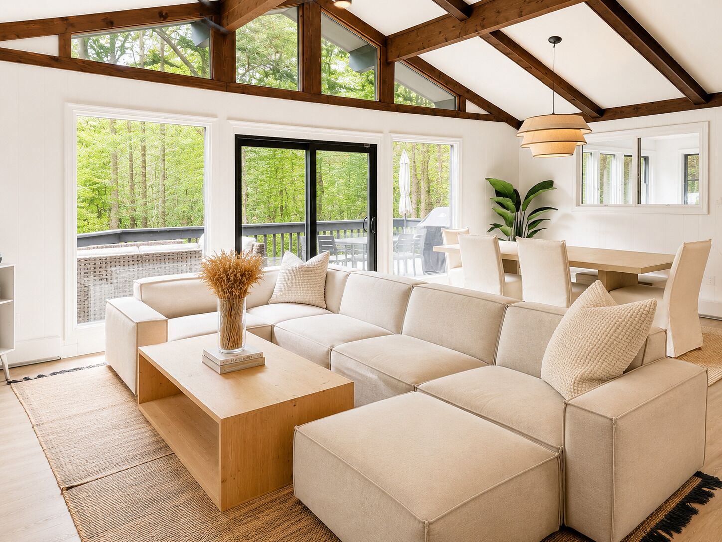 A modern living room with a sectional sofa, a wooden coffee table, and a dining area with a table and chairs.