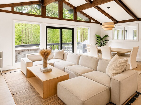 A modern living room with a sectional sofa, a wooden coffee table, and a dining area with a table and chairs.