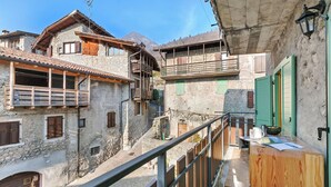 A traditional stone building with wooden balconies and a wooden railing. - Villa Pastoedo Ap. Verde - Balcony & Mountain Views, Tenno, Italy (Tenno)