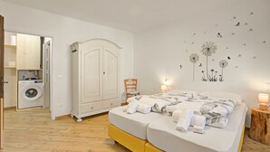 A bedroom with a bed, a wardrobe, a washing machine, and a wall decal. - Villa Pastoedo Ap. Giallo - Terrace & Mountain Views, Tenno, Italy (Tenno)