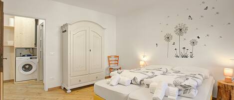 Un dormitorio con cama, armario, lavadora y un adhesivo en la pared.
