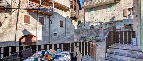Una estrecha calle con edificios de piedra, una mesa dispuesta para comer y una escalera que lleva a un nivel superior.