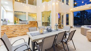 Un espace extérieur aménagé pour les repas, avec un mur en pierre, une table en bois et des chaises.