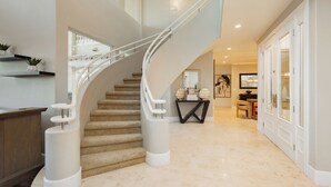 Un intérieur moderne avec un escalier à volutes, un comptoir d’accueil en bois et un couloir menant à une salle à manger.