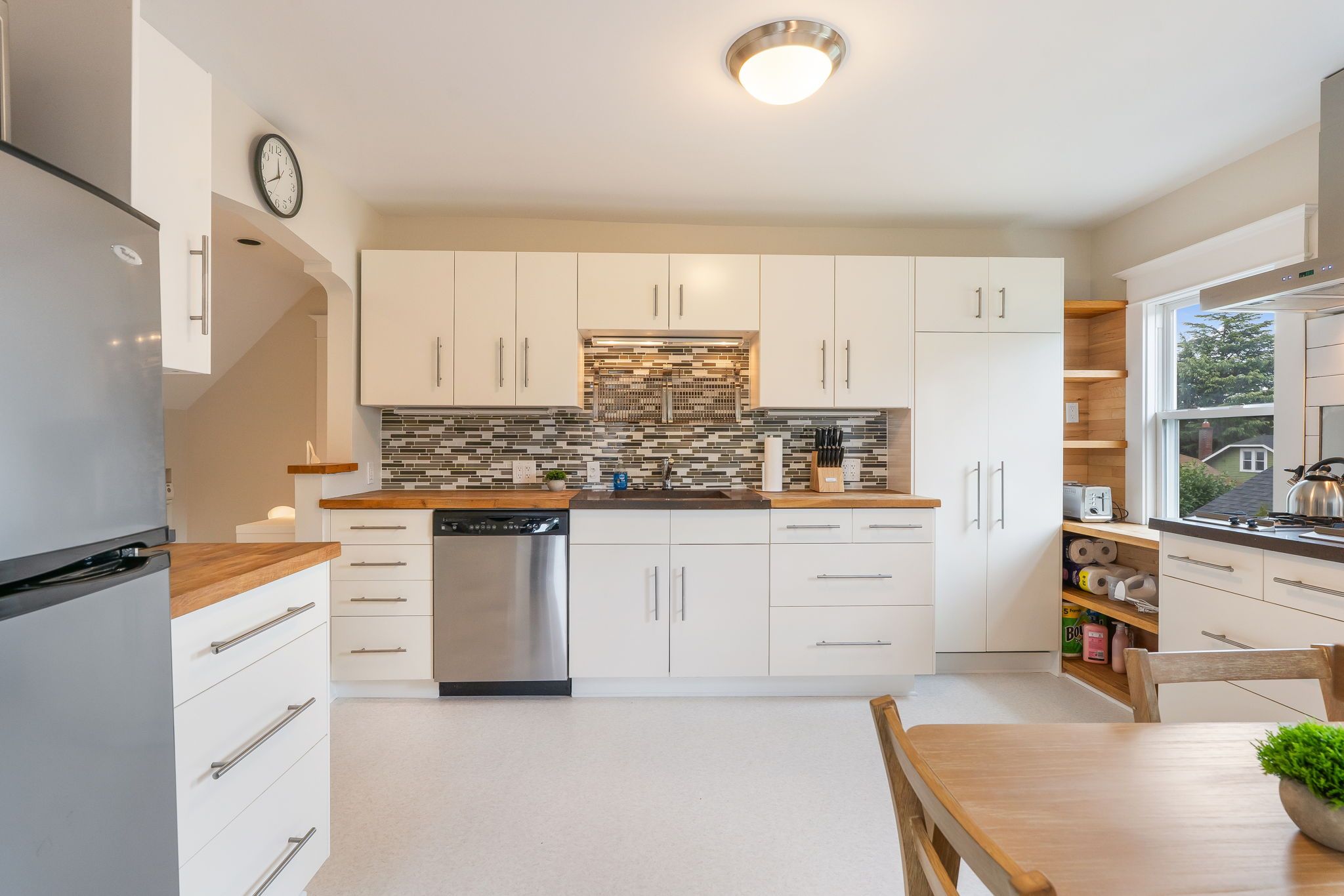 Een moderne keuken met witte kasten, een RVS vaatwasser en een betegelde spatwand.
