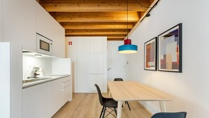 Une cuisine moderne avec des meubles blancs, un plafond en bois et un coin repas comprenant une table et des chaises.