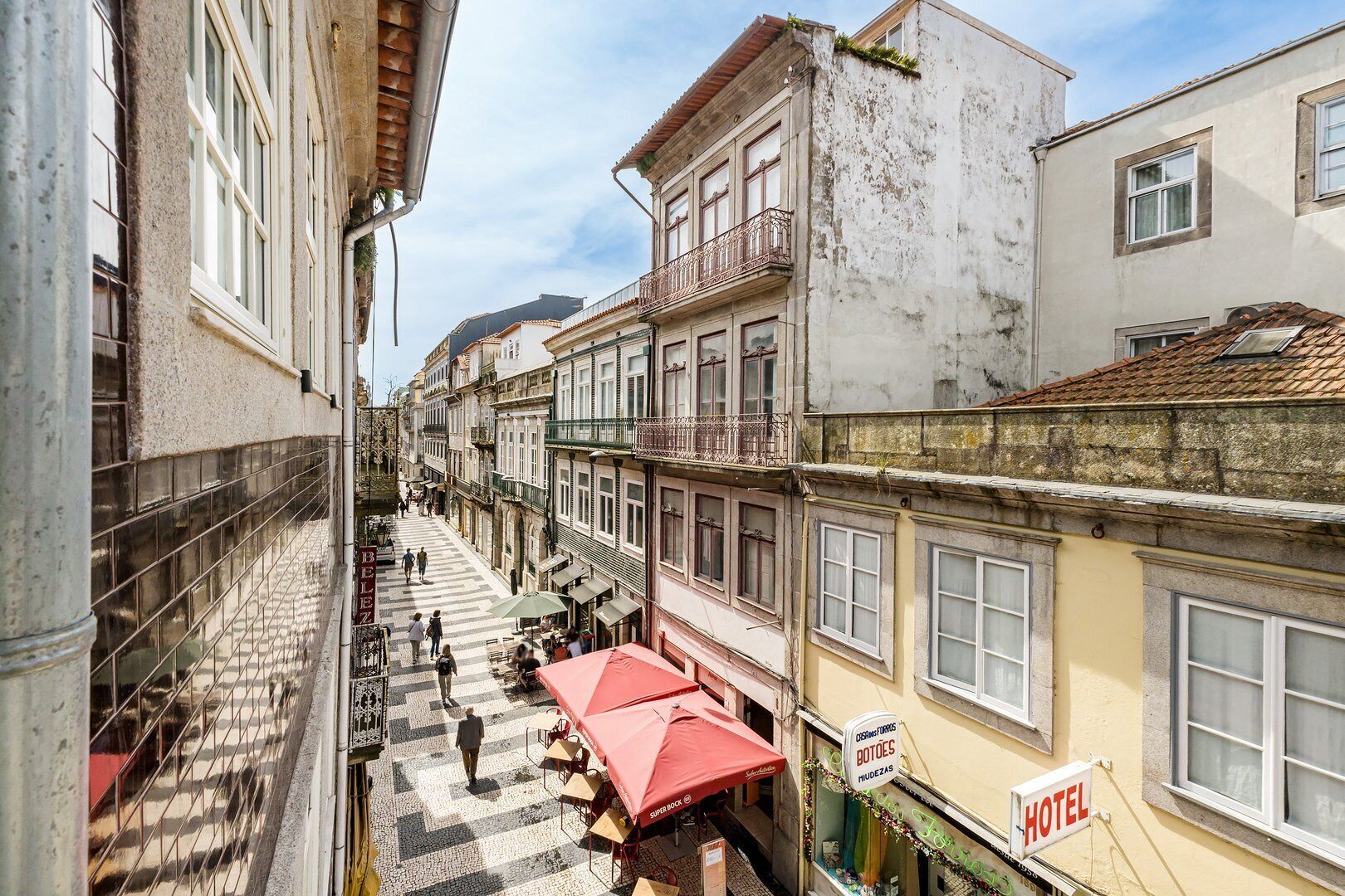 Una calle estrecha flanqueada por edificios, incluyendo un hotel con un cartel.
