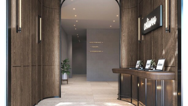 Eine moderne Hotelhalle mit einer Rezeption, Holzwandverkleidung und einem Schild, das Restaurant, Geschäfte und Toiletten kennzeichnet.