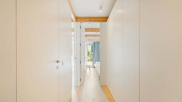 A hallway with white walls, wooden flooring, and a ceiling with exposed beams. - GuestReady - Cedofeita Collection Deluxe P3 (Porto)