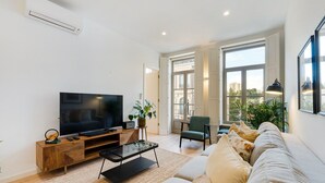 Een moderne woonkamer met een flatscreen televisie, een salontafel, een bank en een fauteuil.