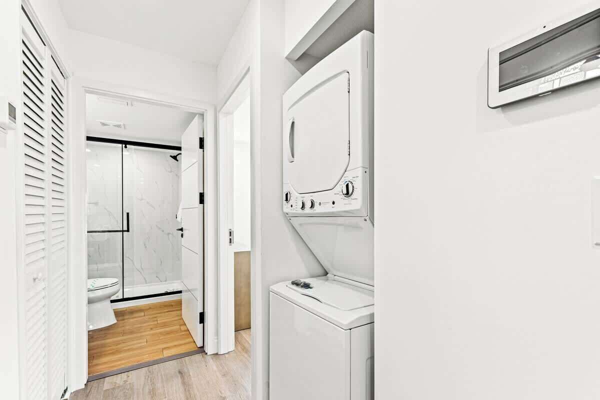 Un baño moderno con cabina de ducha de vidrio, inodoro blanco y lavadora integrada.