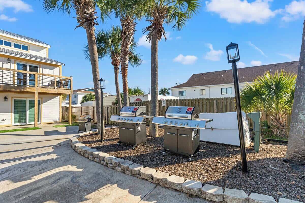 A residential area with a barbecue setup, palm trees, and a street view.