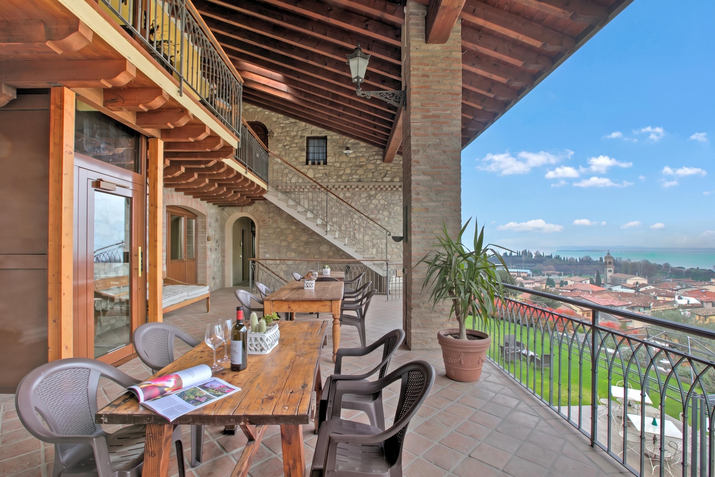 A balcony with a wooden table, chairs, and a potted plant.