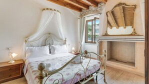 A bedroom with a four-poster bed, a stone fireplace, and a view of the outdoors. - Agriturismo Apartment Vigilio heated pool and AC, Padenghe sul Garda, Italy (Padenghe sul Garda)