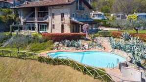 A stone villa with a swimming pool, surrounded by landscaped gardens and a view of neighboring houses. - Agriturismo Apartment Vigilio heated pool and AC, Padenghe sul Garda, Italy (Padenghe sul Garda)