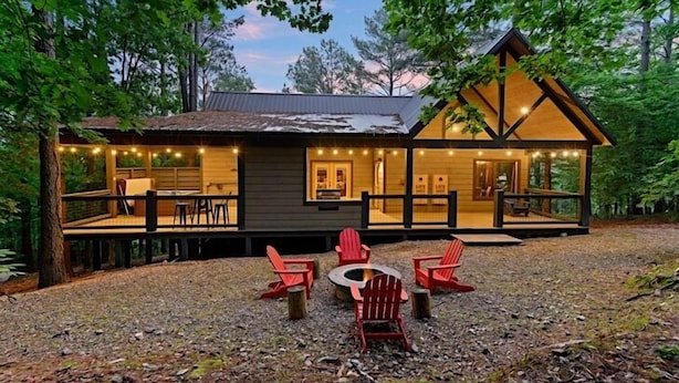 A cabin with a deck, outdoor seating, and a fire pit.
