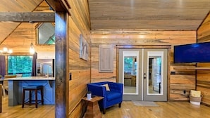 A wooden interior with a bar area, seating, and a television.
