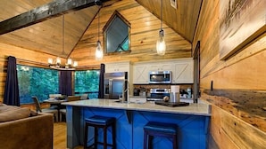 A cozy cabin interior with a wooden interior, a kitchen with modern appliances, and a large island with bar stools.
