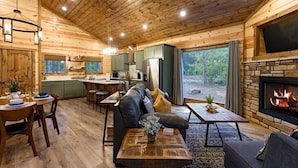 Un espacio habitable espacioso con chimenea, techo de madera y comedor con mesa y sillas.