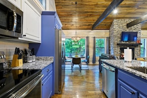 A modern kitchen with granite countertops, a built-in microwave, and a stone fireplace. - Summertime Oasis! Hot Tub|Arcade (Broken Bow)