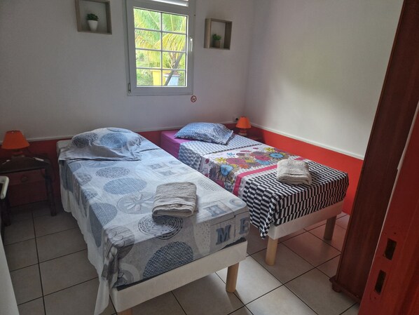 A room with two beds, a nightstand, a window, and a door.