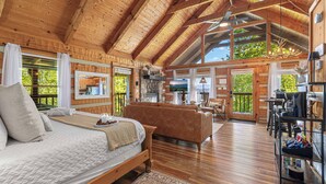 Ein Holzblockhaus-Interieur mit Bett, Sofa und Küchenzeile.