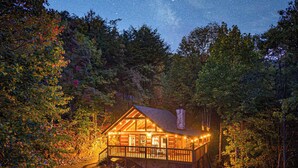 Eine Holzhütte mit einer Holzterrasse, umgeben von Bäumen und einer Steintreppe, die dorthin führt.