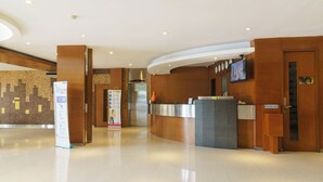 Un moderno vestíbulo de hotel con un mostrador de recepción, una pantalla digital y un plano de planta visible.