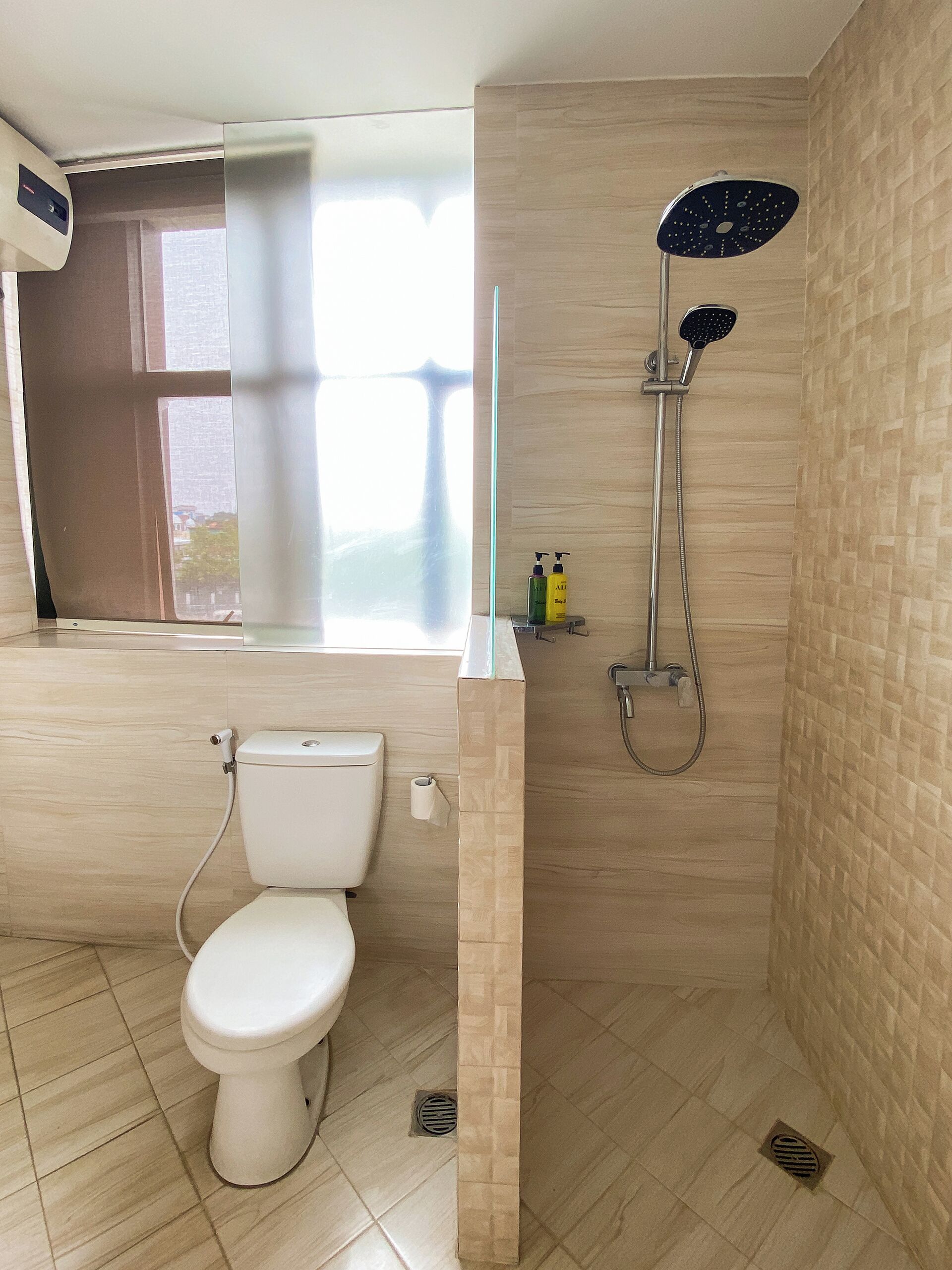 A bathroom with a toilet, a shower, and a window.
