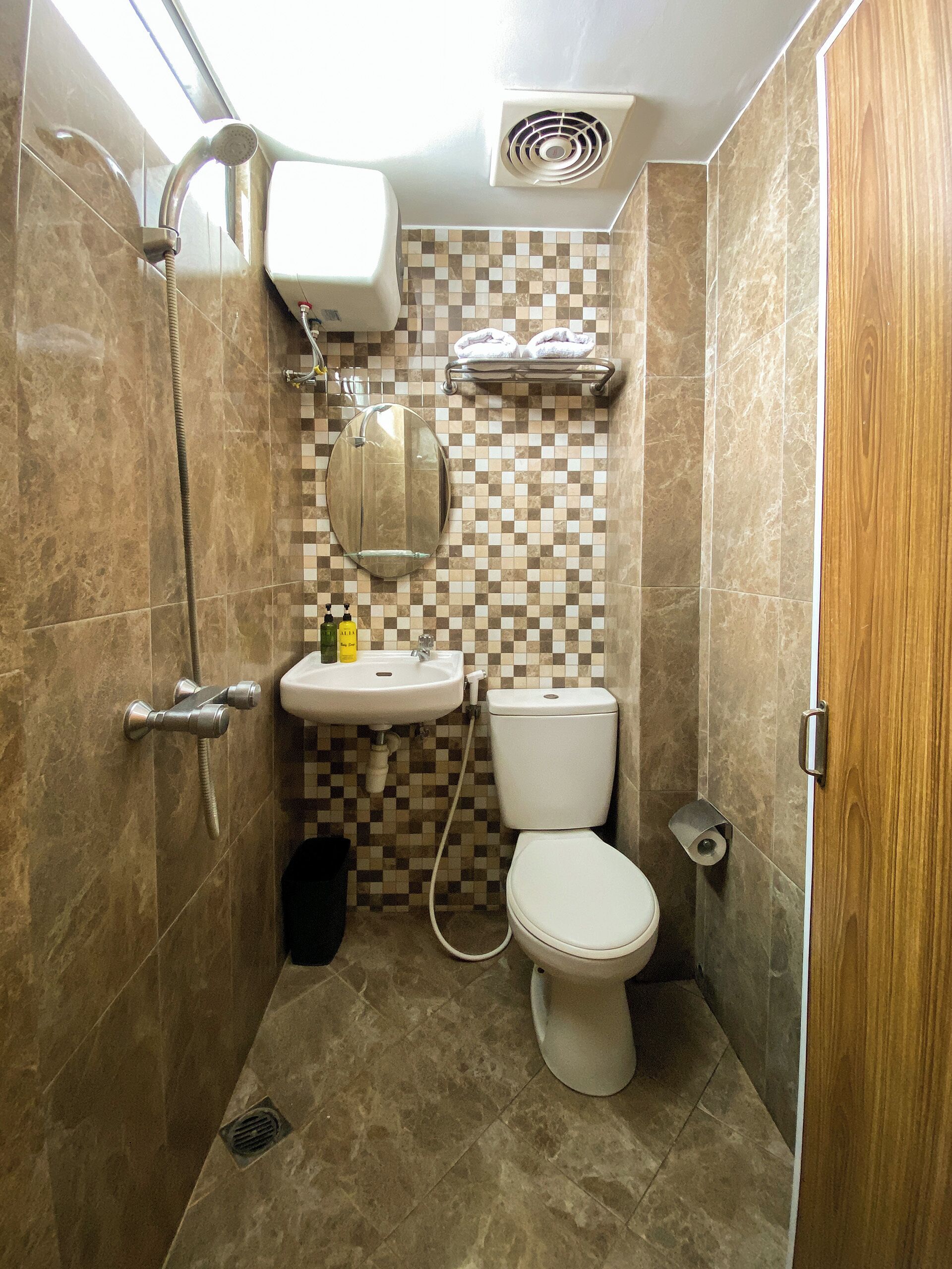 A compact bathroom with a shower, toilet, sink, and a mirror.