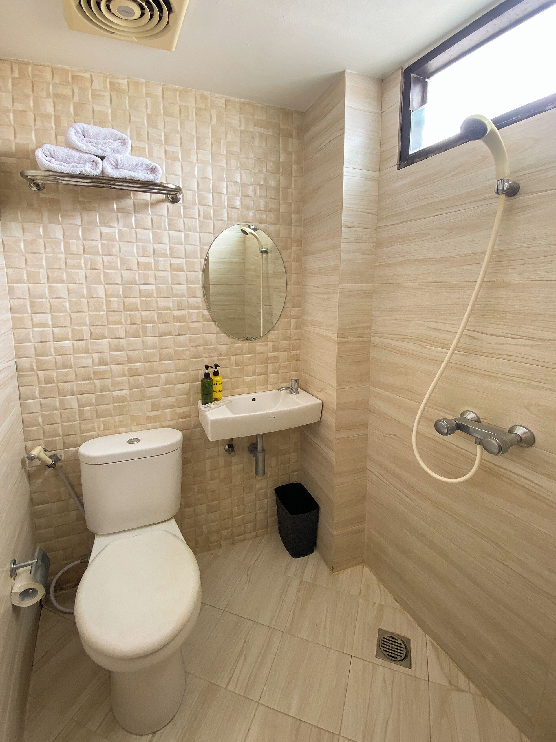 Et badeværelse med toilet, vask og brusebad.