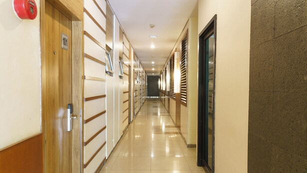 Un pasillo de hotel con puertas de madera, placas con los números de las habitaciones y suelo de baldosas.
