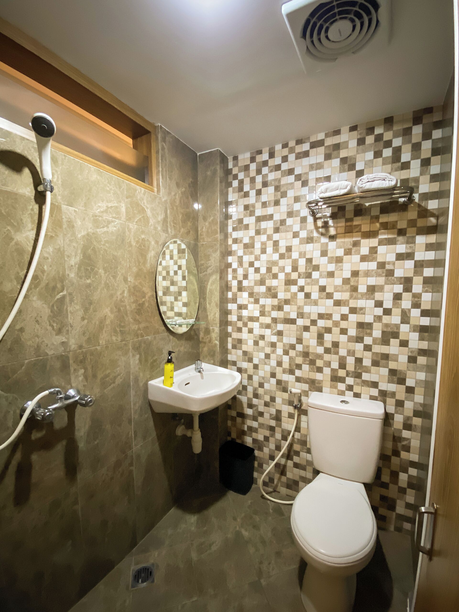A bathroom with a checkered tile wall, a white sink, a toilet, and a shower area.