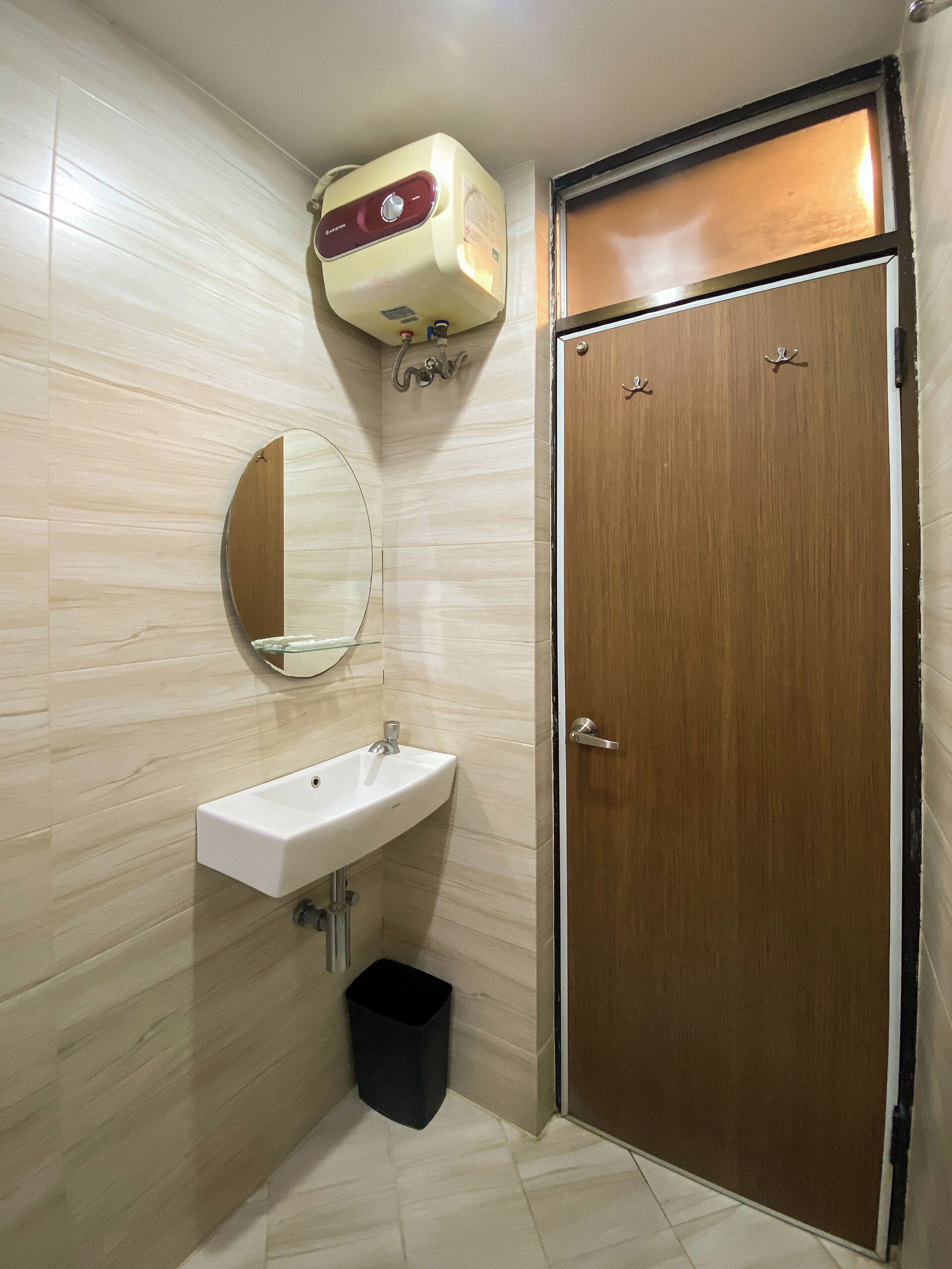A bathroom with a wooden door, a white sink, a mirror, and a towel rack.