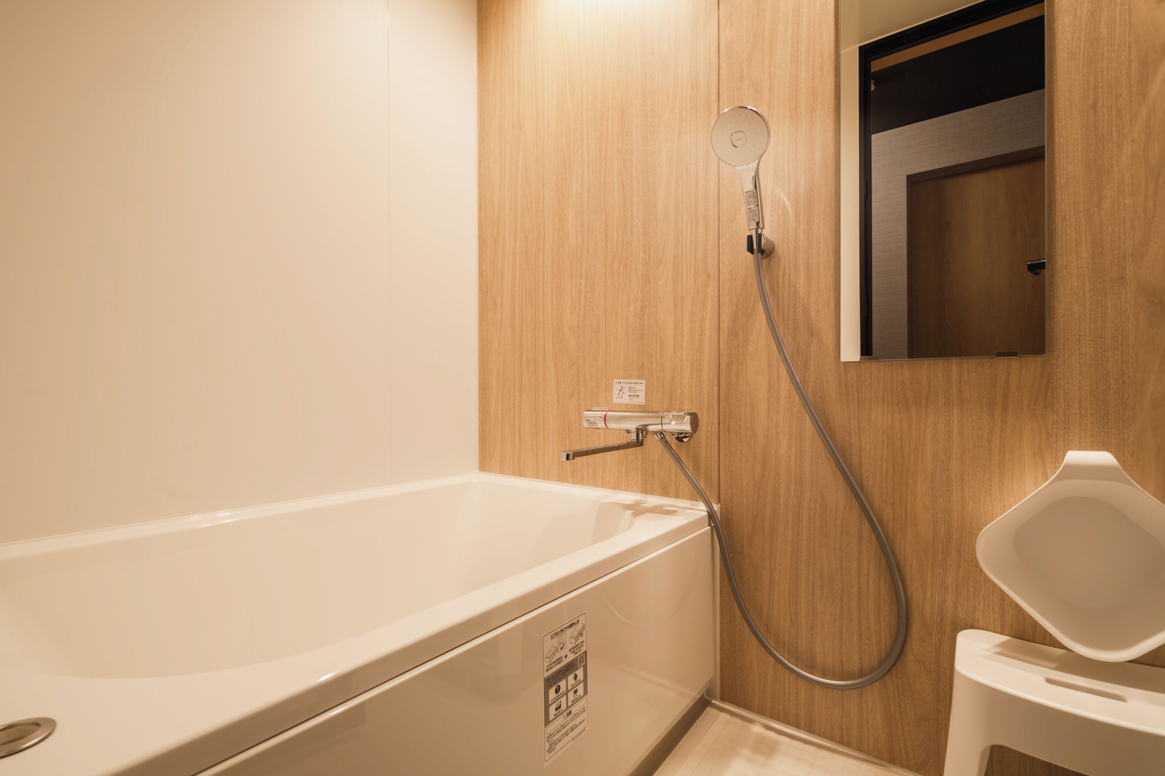 A modern bathroom with a white bathtub, a shower, and a mirror.