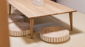 A wooden table with a white object on it, surrounded by woven stools.