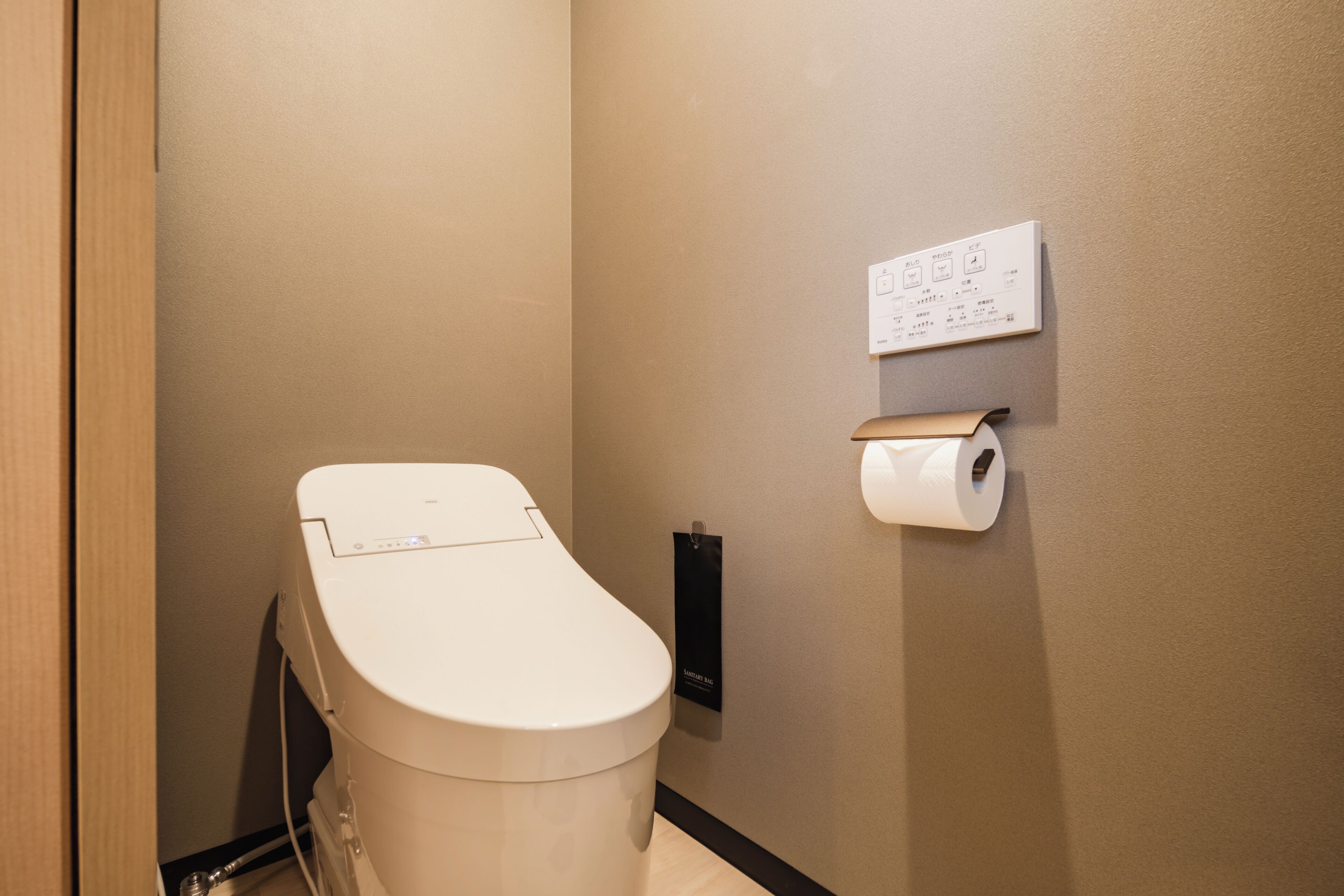 Des toilettes modernes dotées d’un panneau de commande, d’un distributeur de papier toilette et d’un panneau d’information fixé au mur.