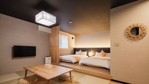 A modern hotel room with a wooden table, two beds, a flat-screen TV, and a decorative mirror. - BEPPU Risana (Beppu)