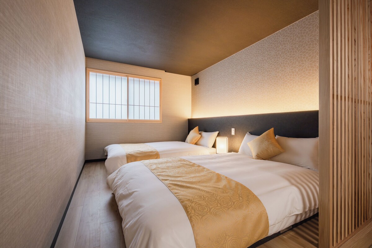 A hotel room with two beds, a large window, and a modern design.