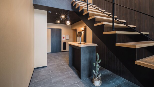 A modern interior with a staircase, a reception desk, and a cactus plant. - BEPPU Risana (Beppu)