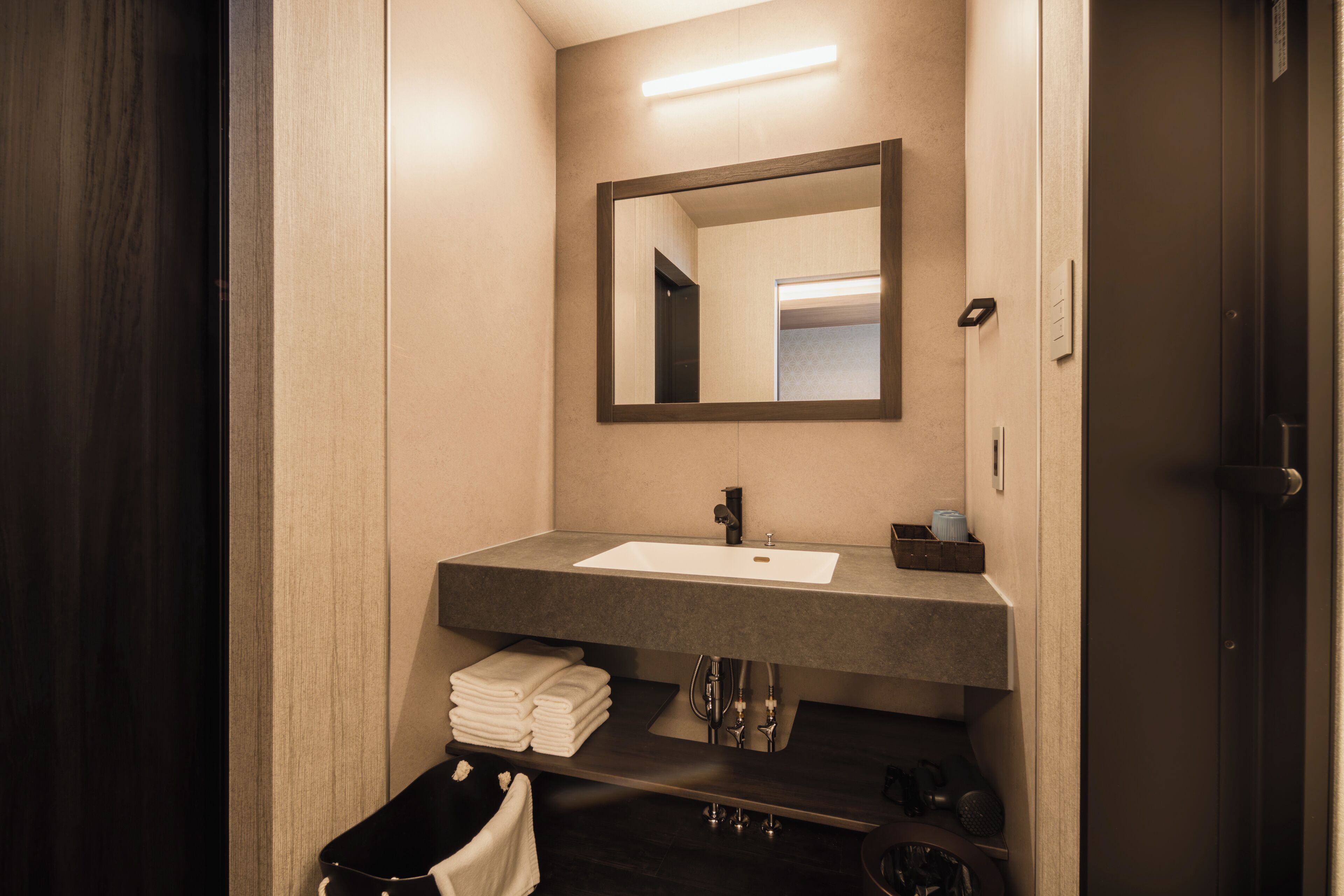 A modern bathroom with a dark wood vanity, a large mirror, and a white sink.