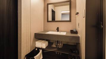 A modern bathroom with a dark wood vanity, a large mirror, and a white sink.